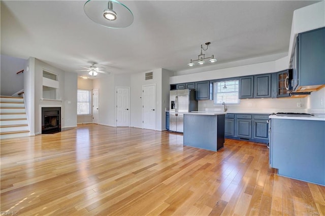 kitchen with a center island, stainless steel refrigerator with ice dispenser, light countertops, visible vents, and light wood-style flooring