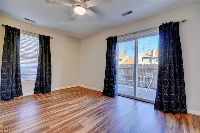 empty room featuring baseboards, visible vents, and wood finished floors