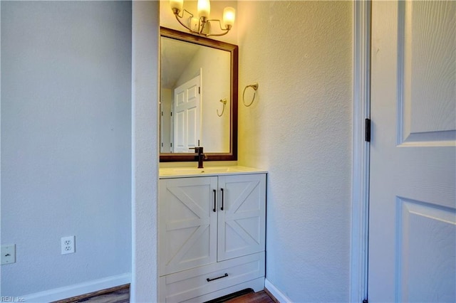 bathroom featuring a textured wall, vanity, and baseboards