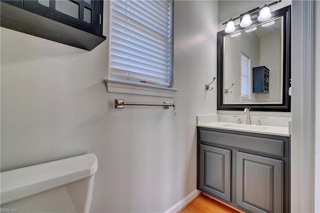 bathroom with wood finished floors, vanity, toilet, and baseboards