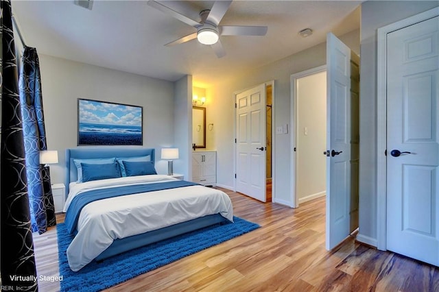 bedroom with a ceiling fan, connected bathroom, light wood-style flooring, and baseboards