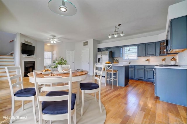 kitchen with a breakfast bar, a center island, a fireplace, light countertops, and blue cabinets