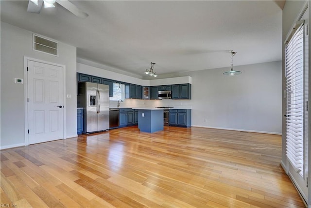 kitchen with stainless steel appliances, visible vents, light countertops, blue cabinetry, and light wood-type flooring