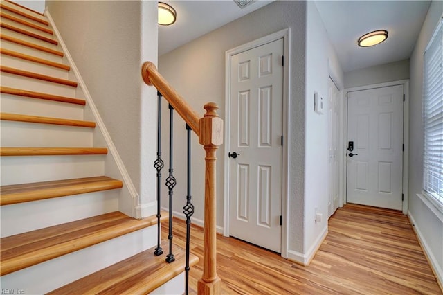 interior space with light wood-style floors, stairs, and baseboards