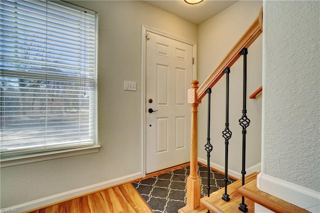 entrance foyer featuring baseboards, stairway, wood finished floors, and a textured wall