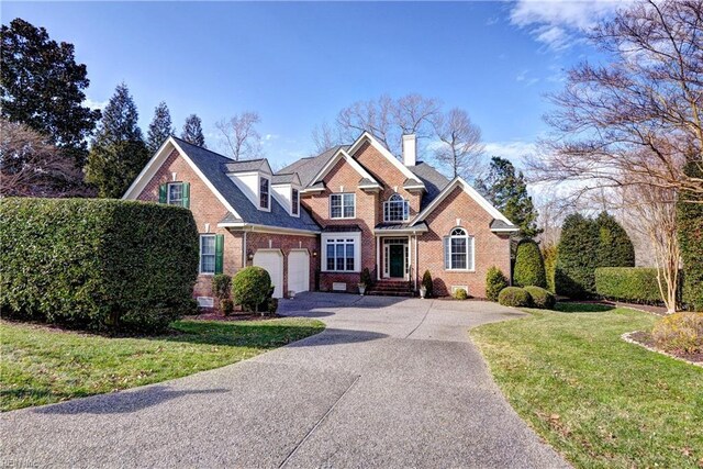 traditional-style house with brick siding, a chimney, a garage, driveway, and a front lawn