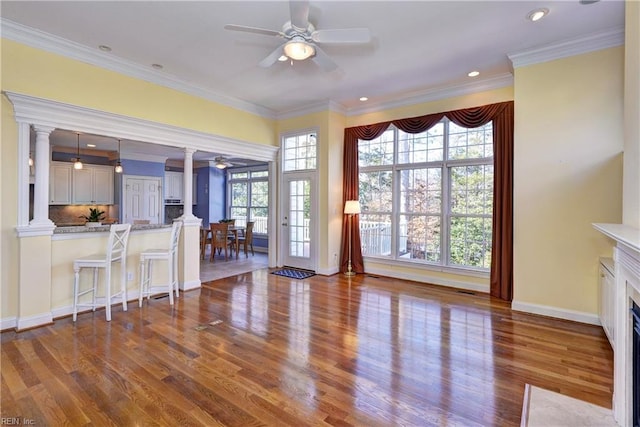 unfurnished living room featuring ornamental molding, dark wood-type flooring, and ornate columns