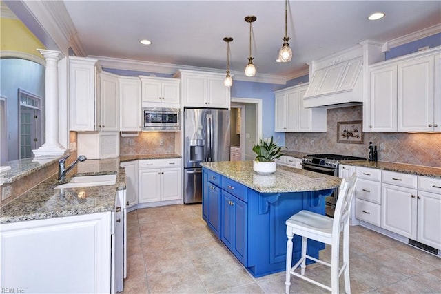 kitchen featuring decorative columns, crown molding, blue cabinetry, stainless steel appliances, and white cabinets