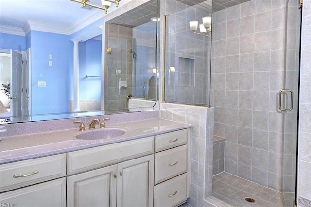 bathroom with a stall shower, decorative columns, crown molding, and vanity