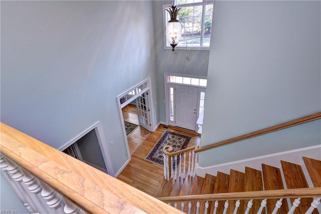 entrance foyer featuring wood finished floors, a towering ceiling, baseboards, and stairs