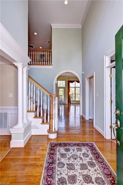 entryway with arched walkways, crown molding, visible vents, wood finished floors, and ornate columns