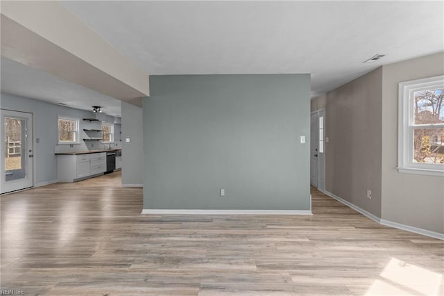 unfurnished living room with a healthy amount of sunlight, visible vents, and light wood-style flooring