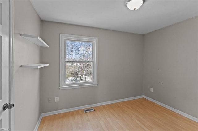 empty room featuring visible vents, baseboards, and wood finished floors