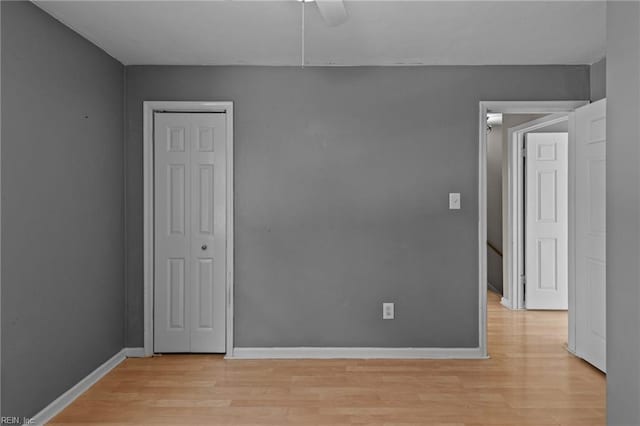 empty room featuring light wood finished floors, baseboards, and a ceiling fan