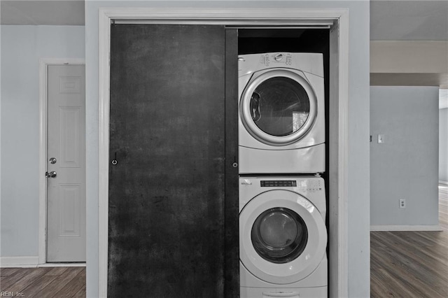 laundry room featuring baseboards, wood finished floors, and stacked washer / drying machine