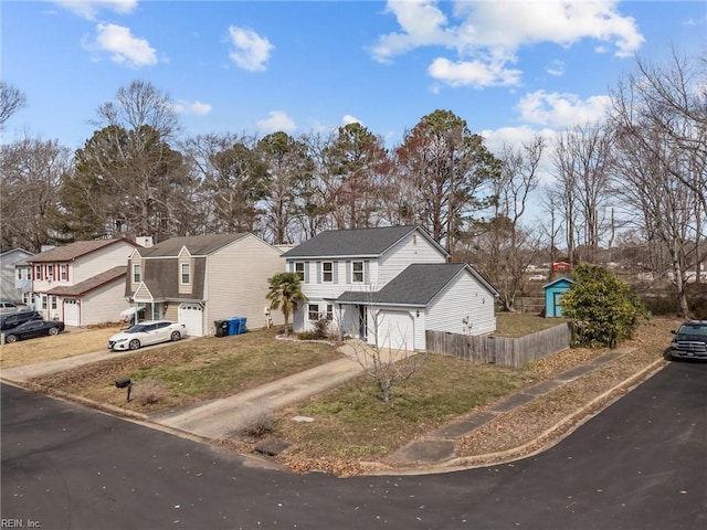 view of front facade featuring a shingled roof, an attached garage, fence, a residential view, and driveway