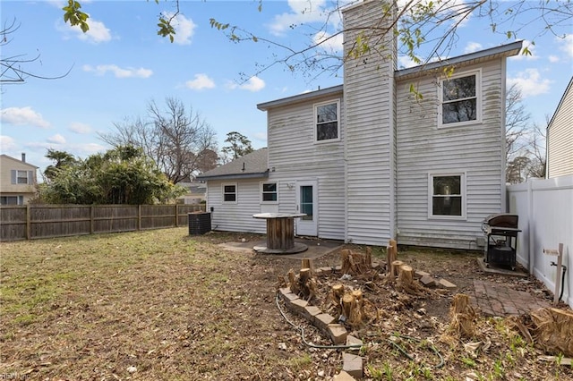 rear view of property with a chimney, a patio area, a fenced backyard, and a lawn