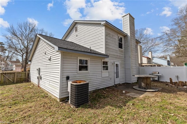 back of property featuring cooling unit, a yard, a chimney, and fence private yard