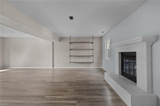 unfurnished living room with a fireplace, wood finished floors, and baseboards