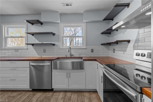 kitchen featuring visible vents, appliances with stainless steel finishes, wooden counters, open shelves, and a sink