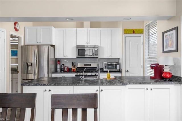 kitchen featuring stainless steel appliances, a toaster, dark countertops, and decorative backsplash