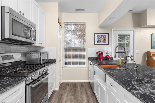 kitchen featuring stainless steel appliances, visible vents, plenty of natural light, and white cabinetry