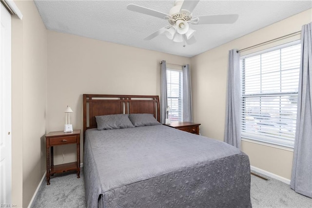 bedroom featuring carpet floors, a textured ceiling, baseboards, and a ceiling fan