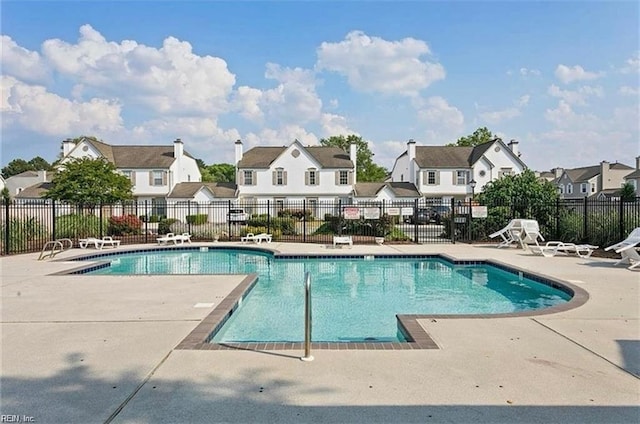 community pool with a residential view, a patio, and fence