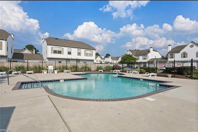 community pool featuring a patio area, a residential view, and fence