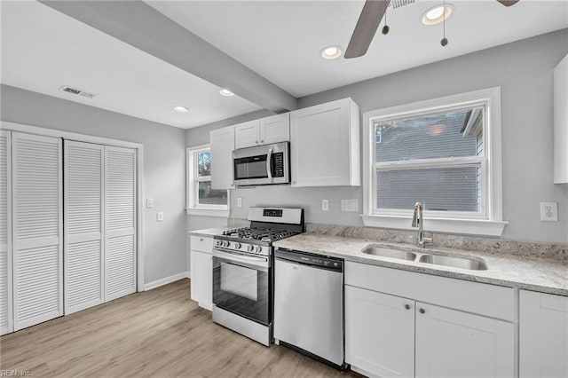 kitchen with visible vents, white cabinets, ceiling fan, stainless steel appliances, and a sink