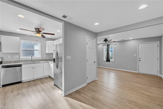 kitchen with a sink, a ceiling fan, light wood-style floors, white cabinets, and appliances with stainless steel finishes