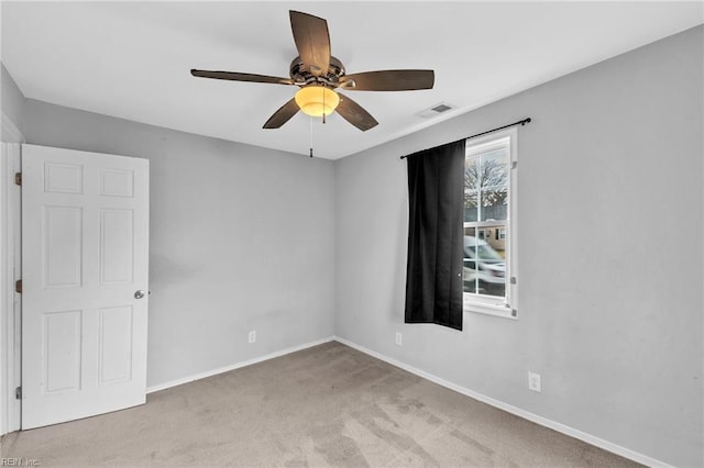 spare room featuring carpet flooring, ceiling fan, visible vents, and baseboards