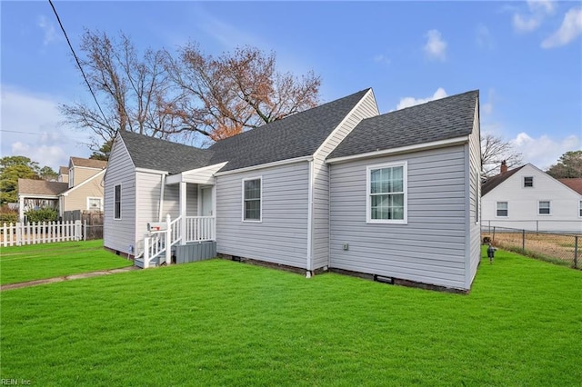 rear view of property featuring fence private yard, roof with shingles, and a yard