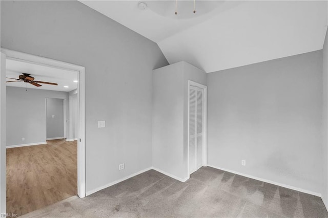 carpeted spare room with vaulted ceiling, a ceiling fan, and baseboards