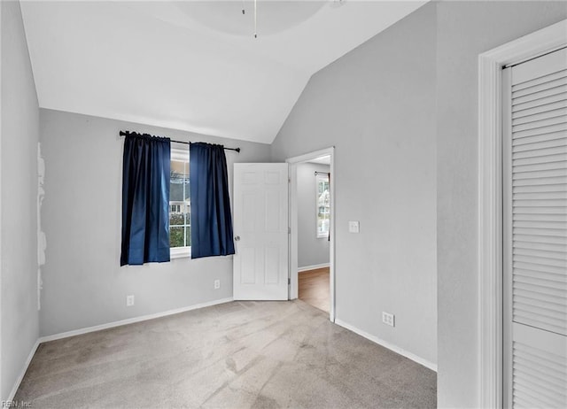 unfurnished bedroom featuring lofted ceiling, carpet, and baseboards