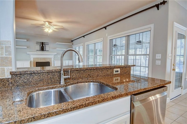 kitchen with dishwasher, a tile fireplace, stone countertops, and a sink