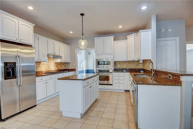 kitchen with light tile patterned floors, appliances with stainless steel finishes, a peninsula, under cabinet range hood, and a sink