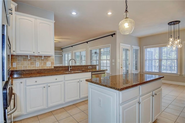 kitchen featuring dishwasher, tasteful backsplash, light tile patterned floors, and a sink