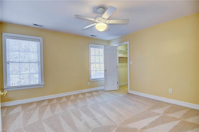 unfurnished room with baseboards, a healthy amount of sunlight, visible vents, and light colored carpet