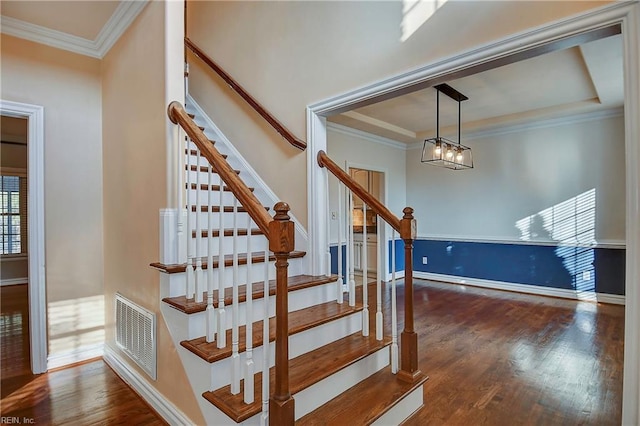 stairs featuring ornamental molding, wood finished floors, visible vents, and baseboards