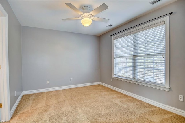 empty room featuring carpet, visible vents, baseboards, and ceiling fan