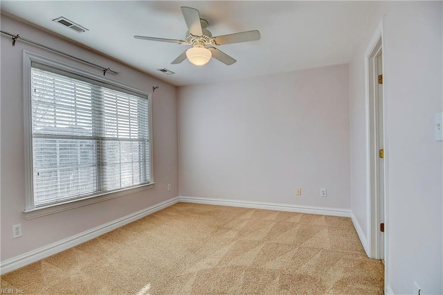 spare room featuring baseboards, visible vents, a ceiling fan, and light colored carpet