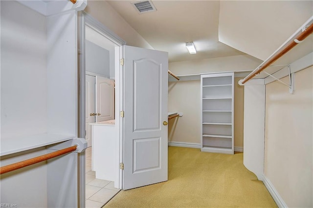 walk in closet featuring visible vents, light carpet, and light tile patterned flooring