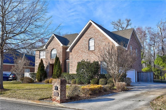 view of front of property featuring concrete driveway, an attached garage, fence, a front lawn, and brick siding