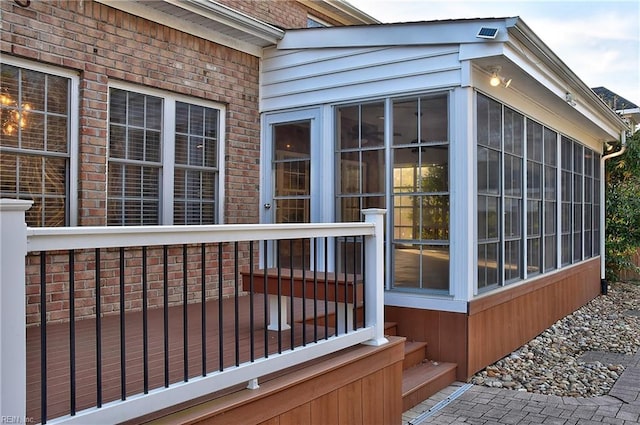 view of home's exterior with a sunroom and brick siding