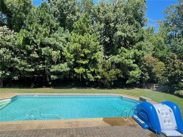 outdoor pool featuring a lawn