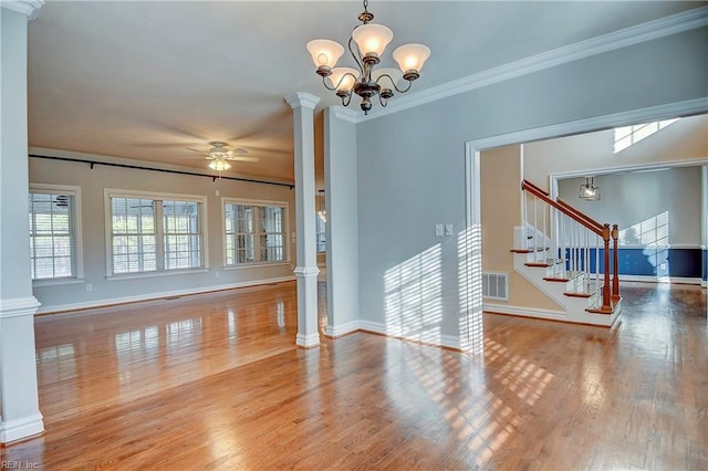 unfurnished living room featuring decorative columns, visible vents, stairway, ornamental molding, and wood finished floors