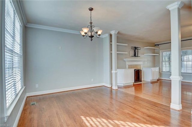 unfurnished living room featuring ornamental molding, light wood-style flooring, and ornate columns