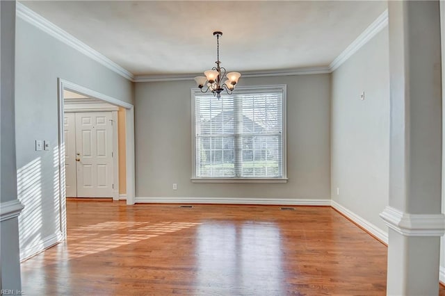 unfurnished dining area with wood finished floors, baseboards, ornamental molding, decorative columns, and an inviting chandelier