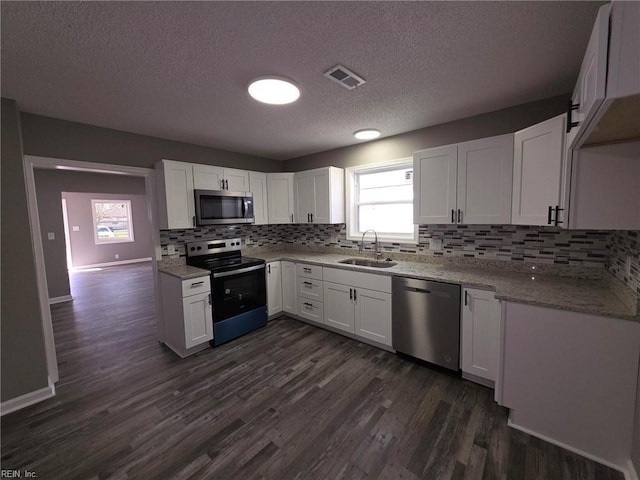 kitchen featuring appliances with stainless steel finishes, visible vents, a sink, and dark wood-style floors